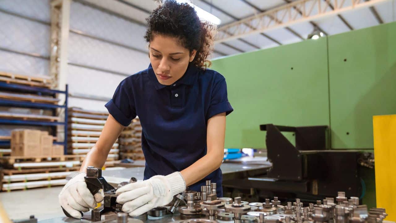 Woman worker in UK manufacturing unit with blue t-shirt and curly tied back hair