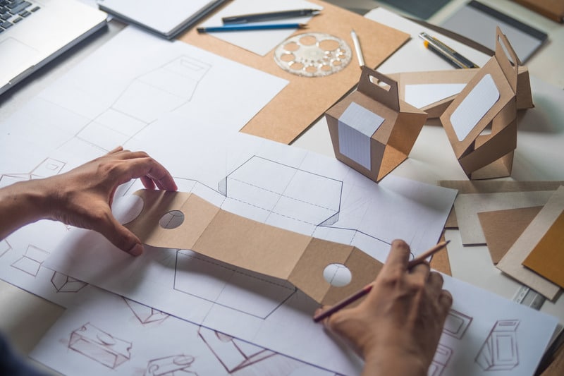 Packaging design ideas process shown by a man working with a cardboard mockup